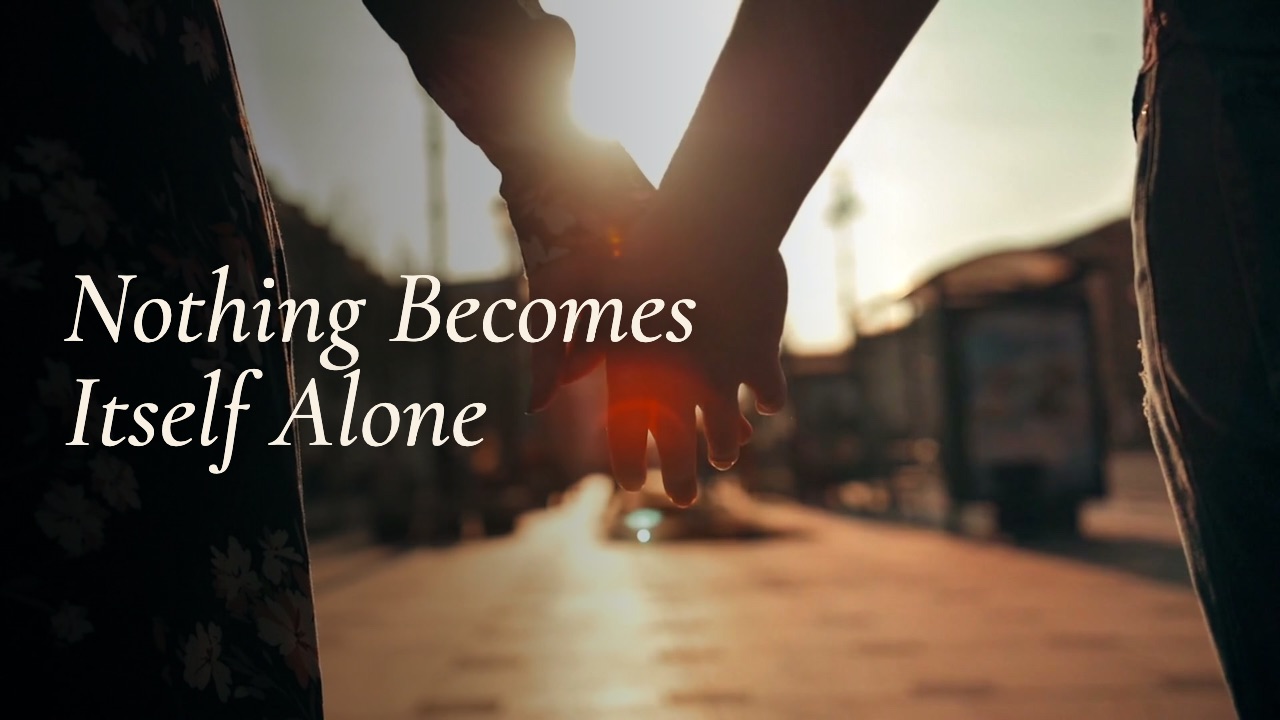 Two hands joining in golden light: a still from the film